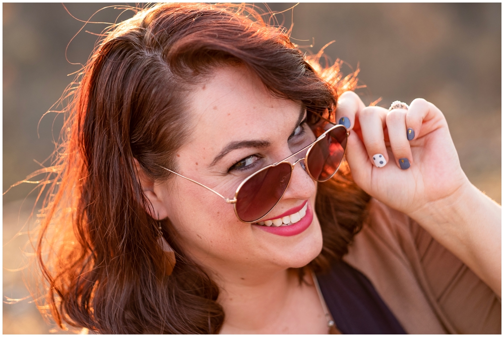 woman pulling down her sunglasses and smiling at camera