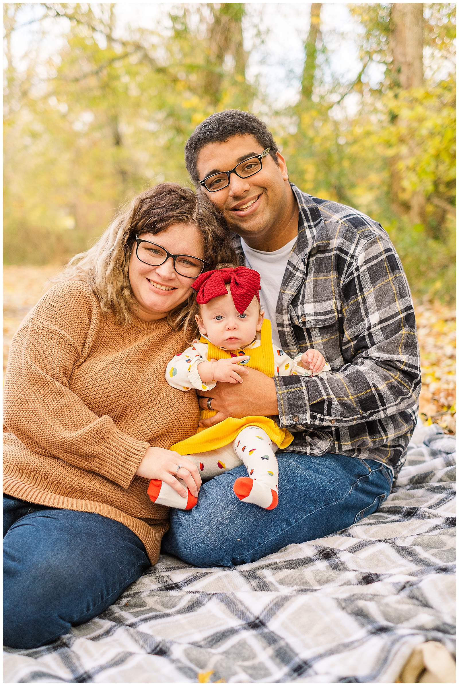 family of three cuddling on the ground for their first portraits