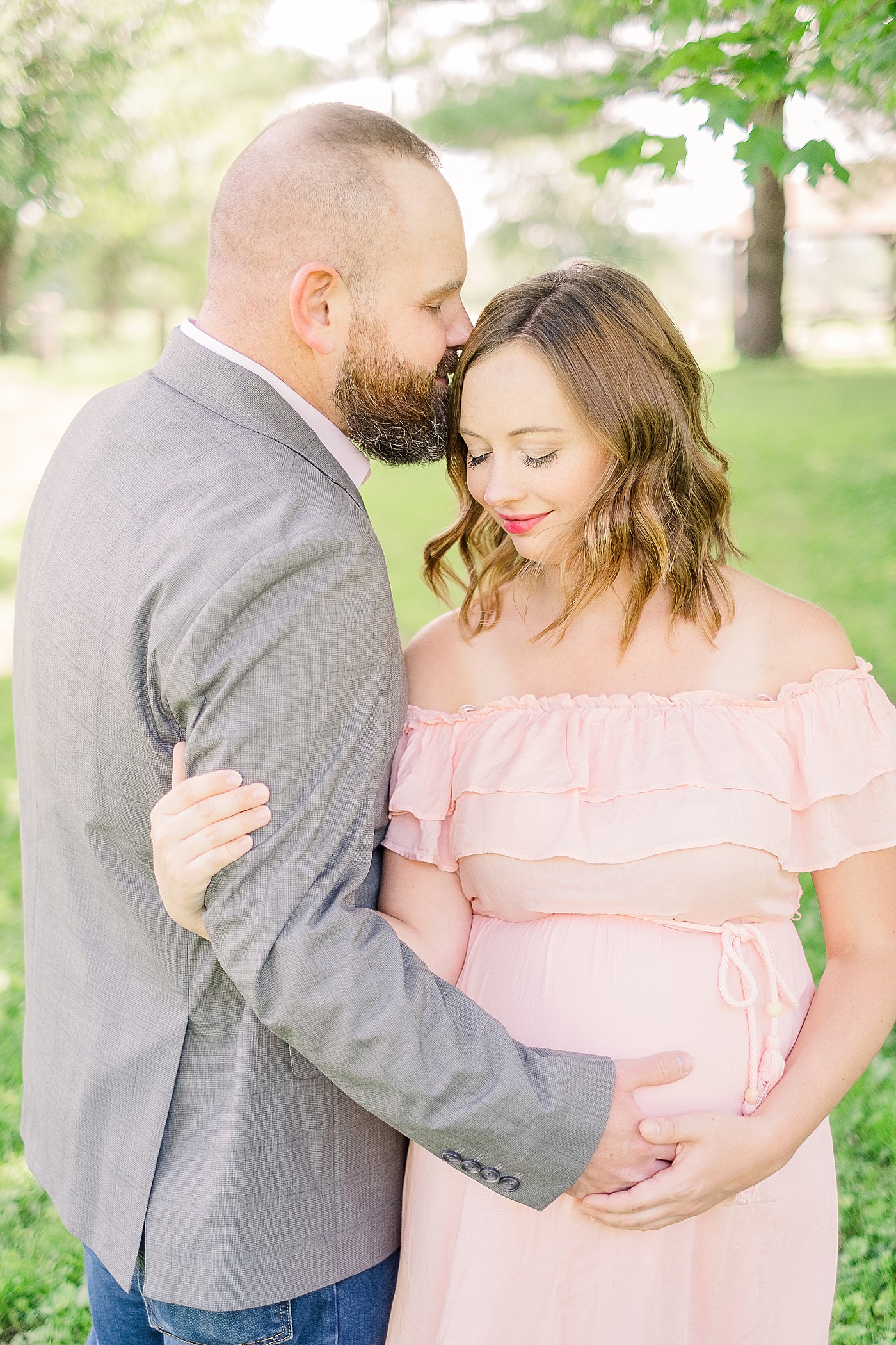 maternity session where dad kisses mom and holds her belly