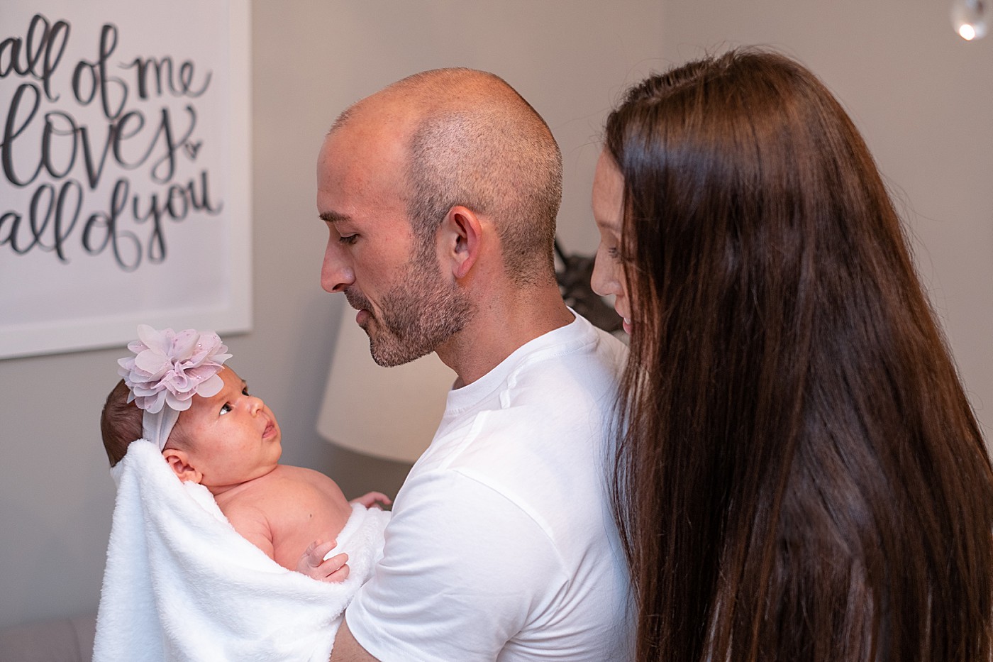 family portrait with dad holding baby in his arms and mom looking over his shoulder