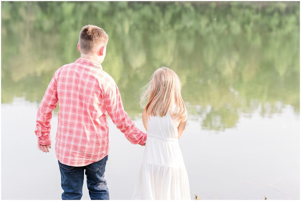 brother and sister holding hands by the lake