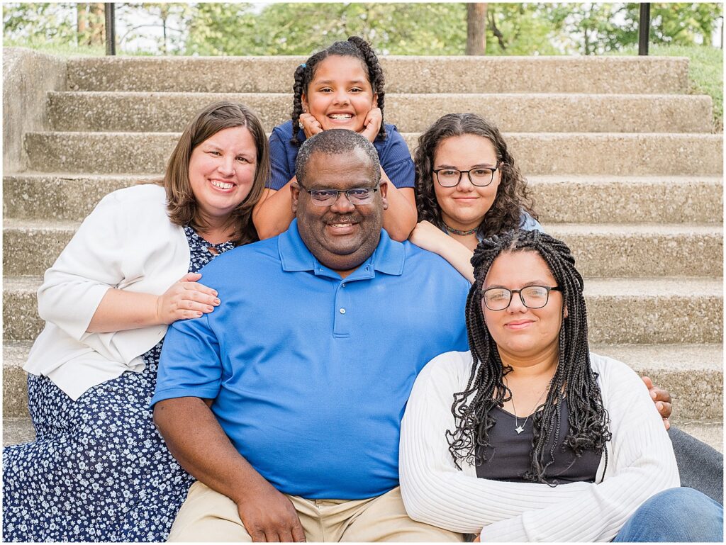 three girl surrounding mom and dad on the steps during their family session