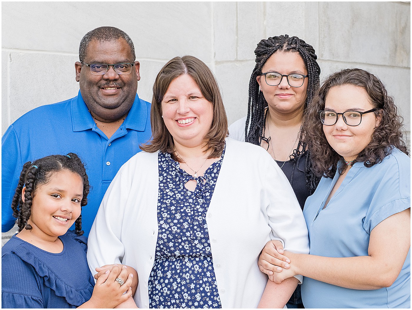 family of five dressed in blue and white all cuddled together and smiling at the camera