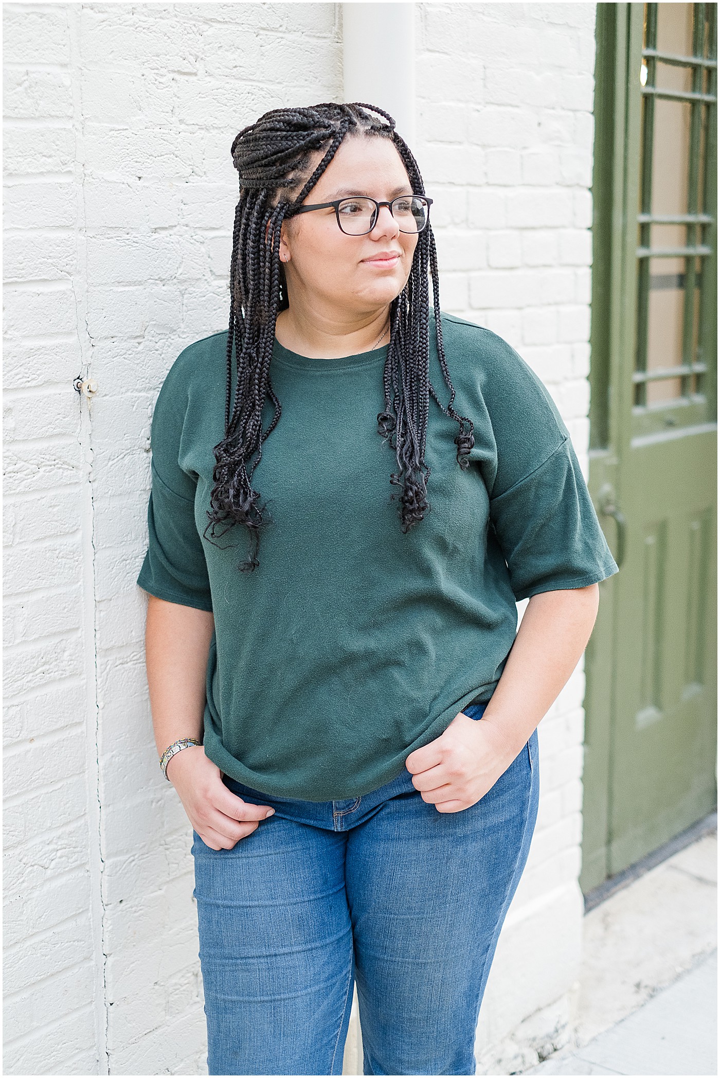 girl in green tee shirt with thumbs in pockets looking off to the right