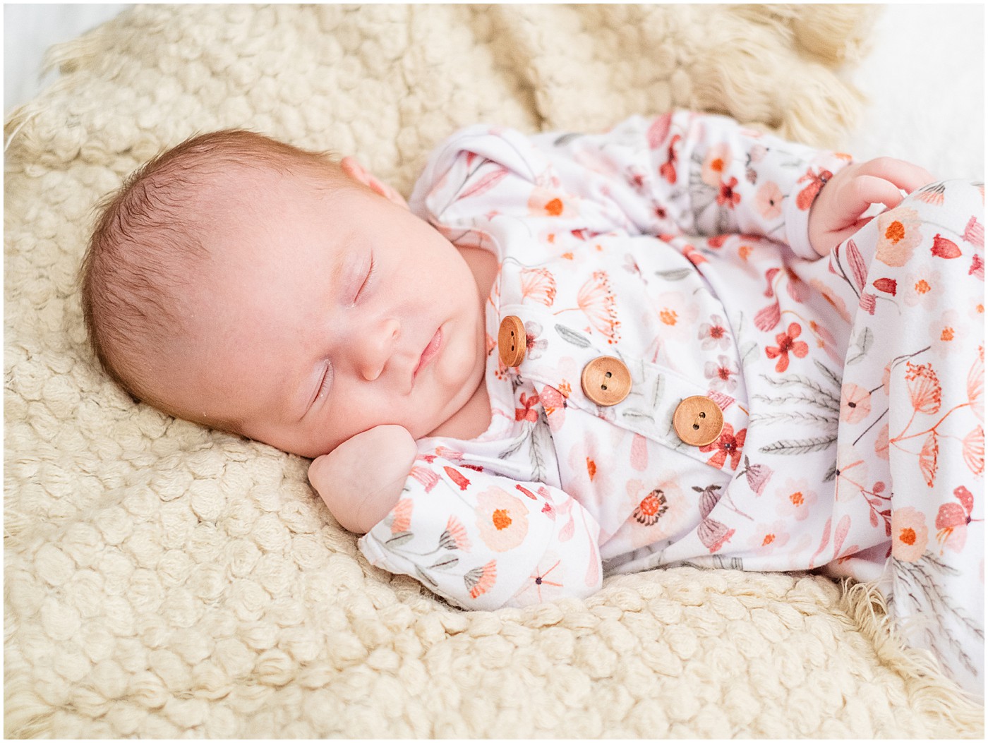 newborn sleeping with fist up to its cheek