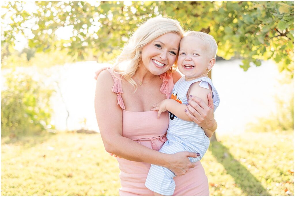 young mom in pink dress cuddling son in blue striped jumpsuit