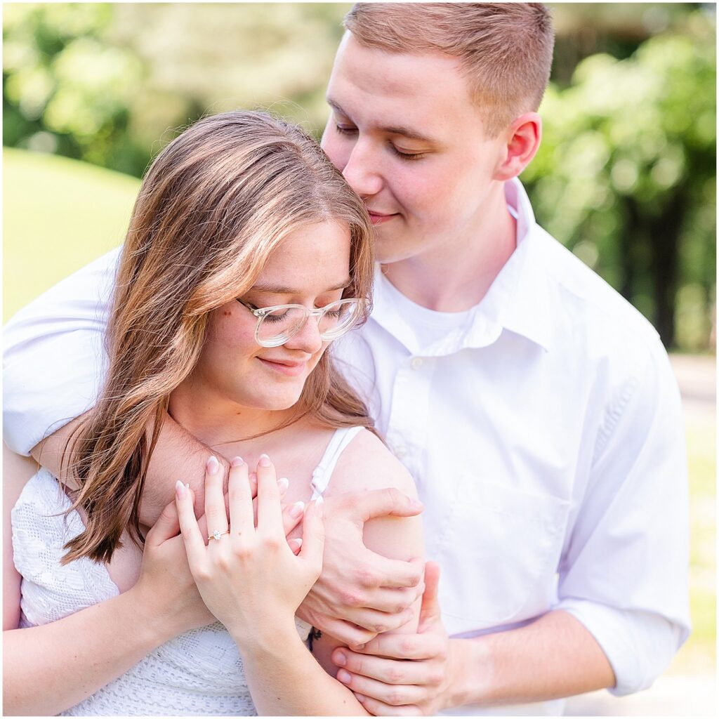 man embraces his fiancee from behind during their outdoorsy engagement session