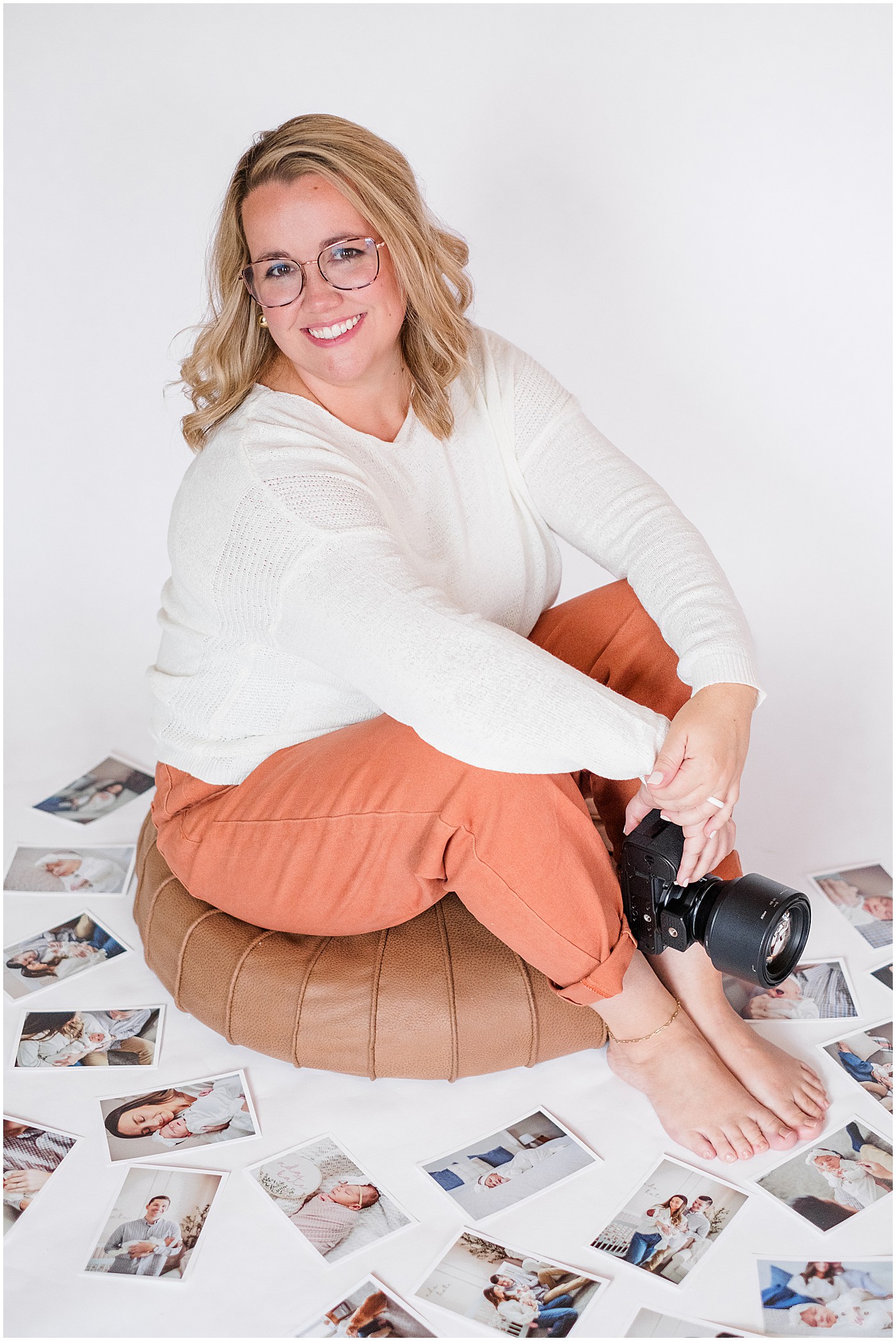 photographer sitting with her camera and surrounded by prints