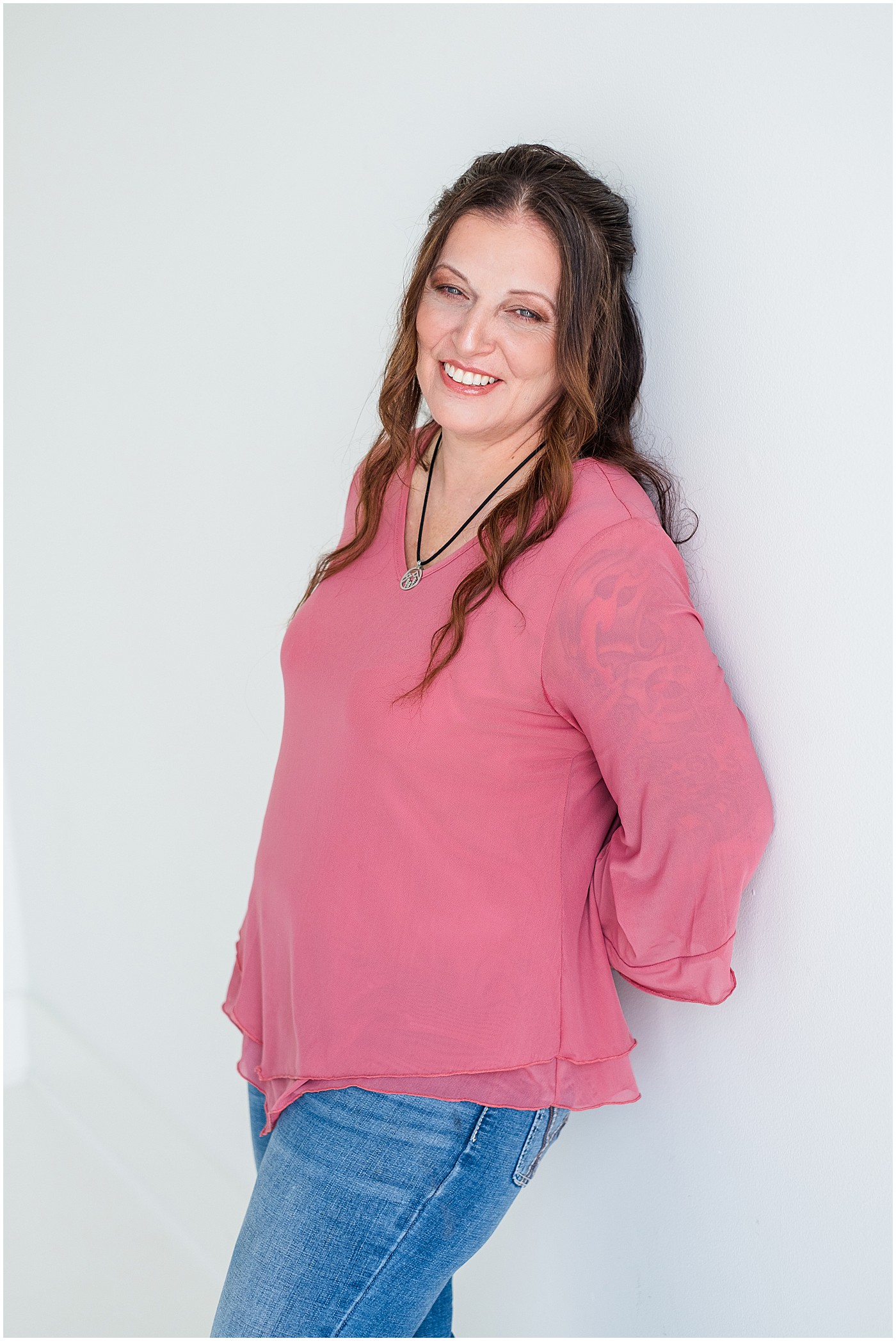 Berea photographer in a pink shirt leaning against wall in headshot