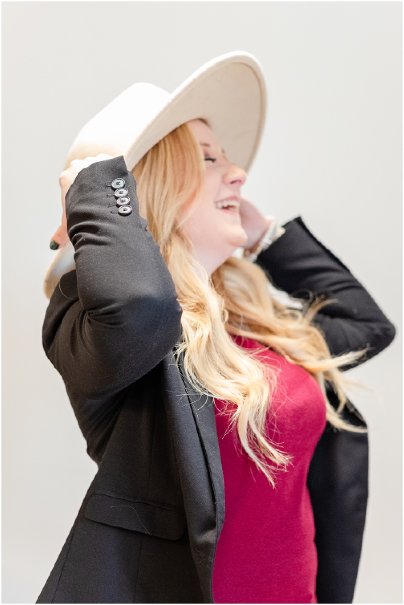 photography branding session where photographer is holding on to her hat and laughing