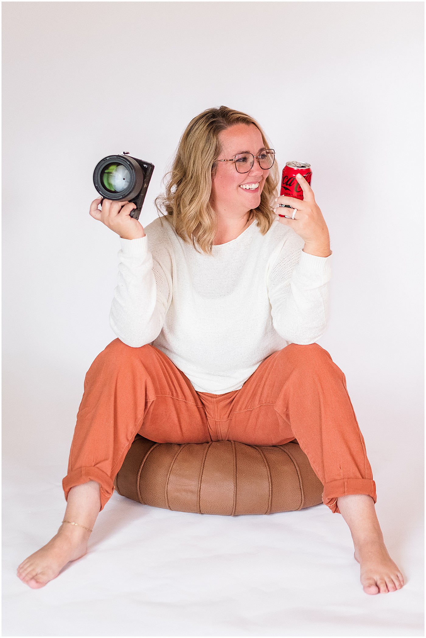 photographer with camera in one hand and a diet coke in the other on her photography branding session