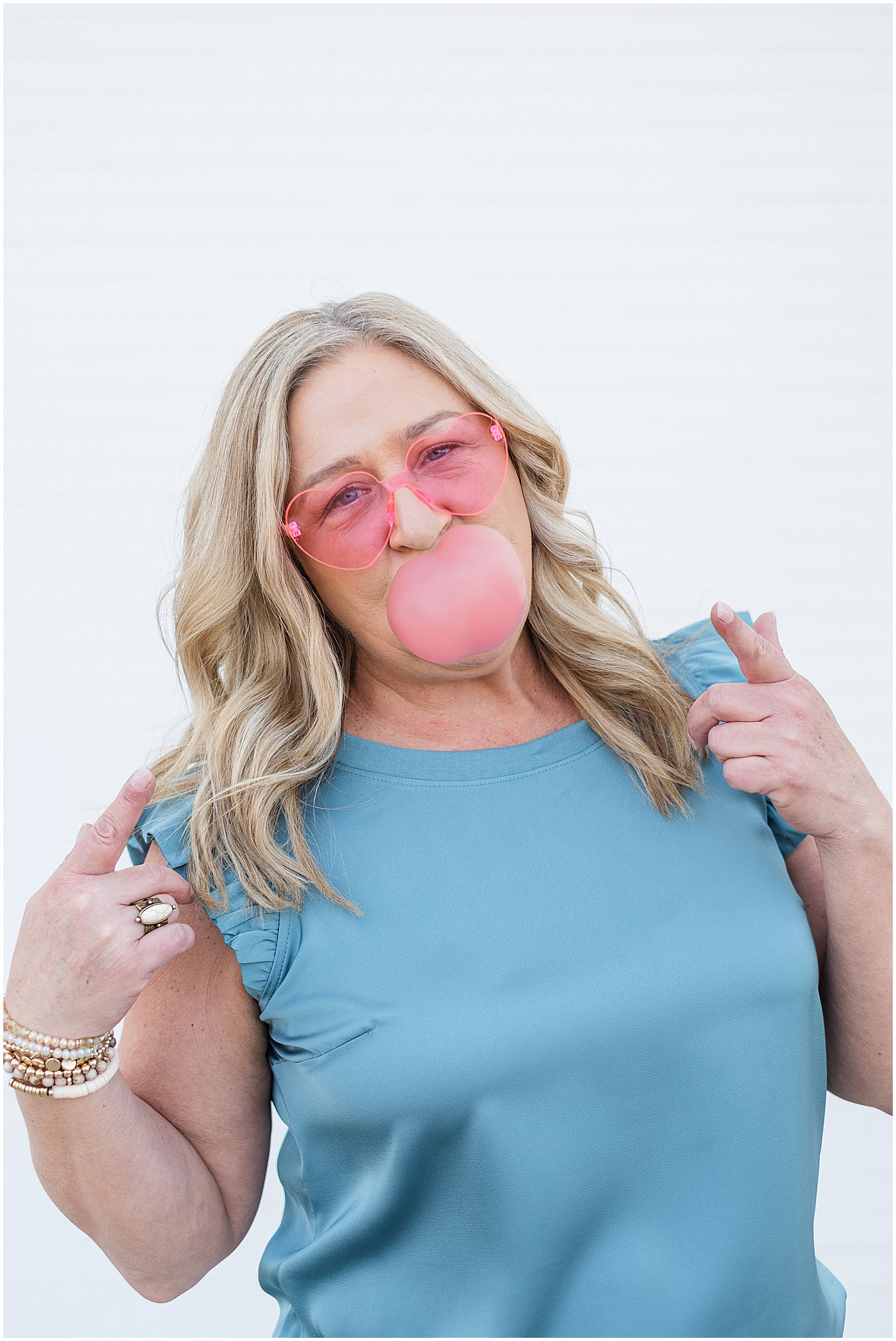 photography branding photo wearing pink heart sunglasses and blowing bubblegum bubble