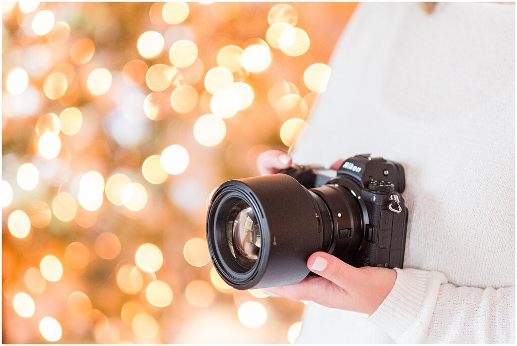 photographer holding a camera with Christmas lights in the background