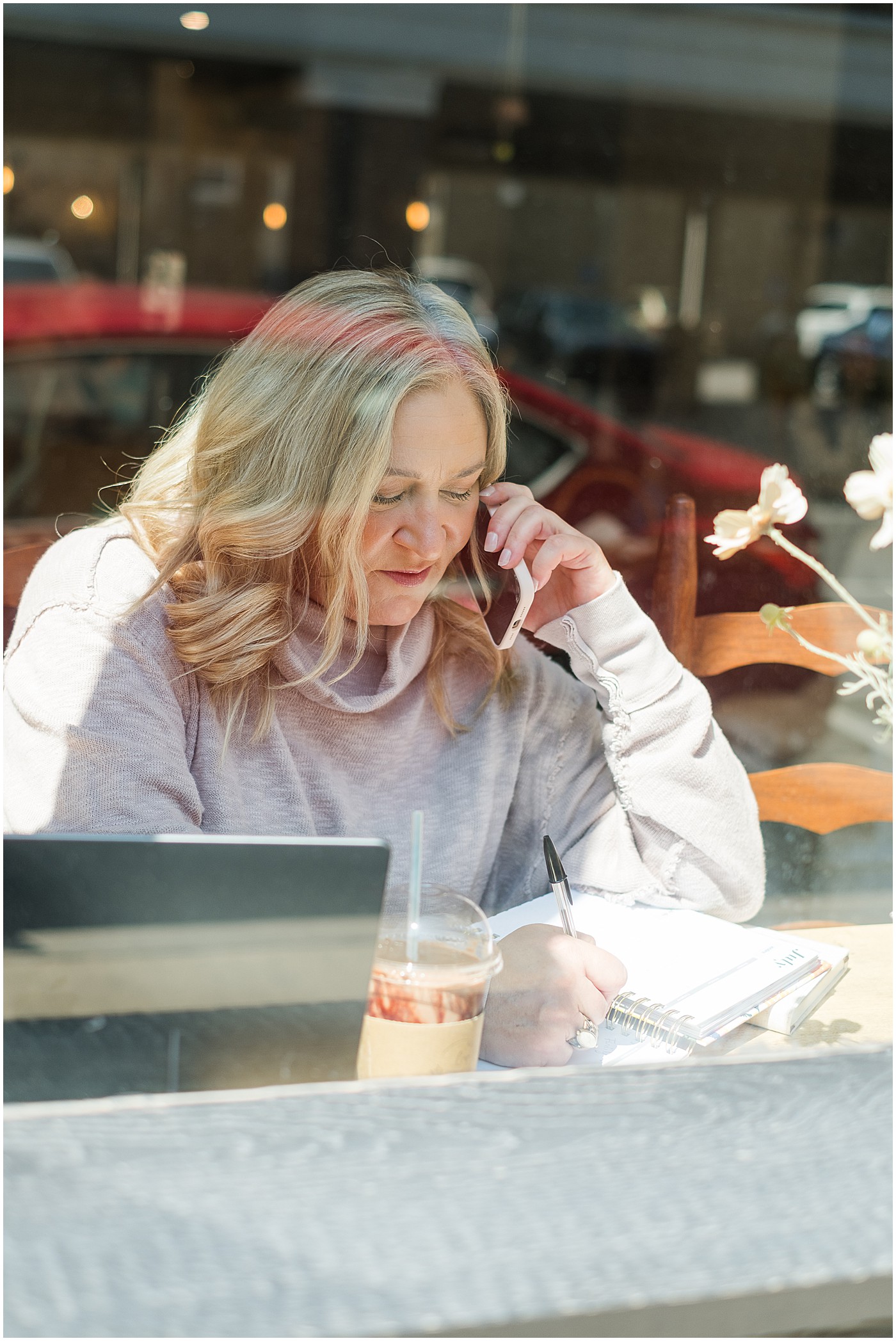 photographer talking on the phone, taken through coffee shop window during her photography branding session