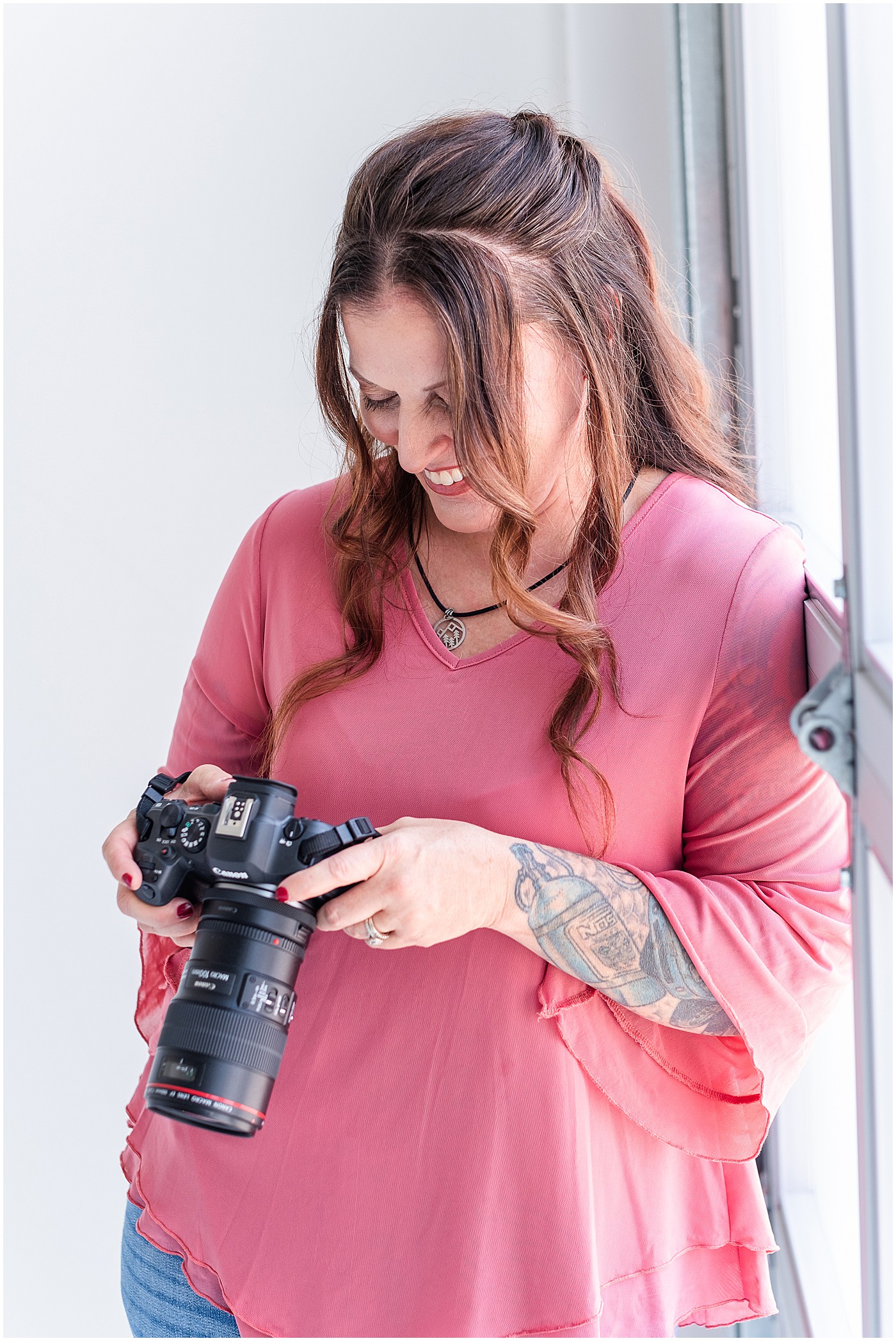 photographer in pink shirt looking at the back of her camera