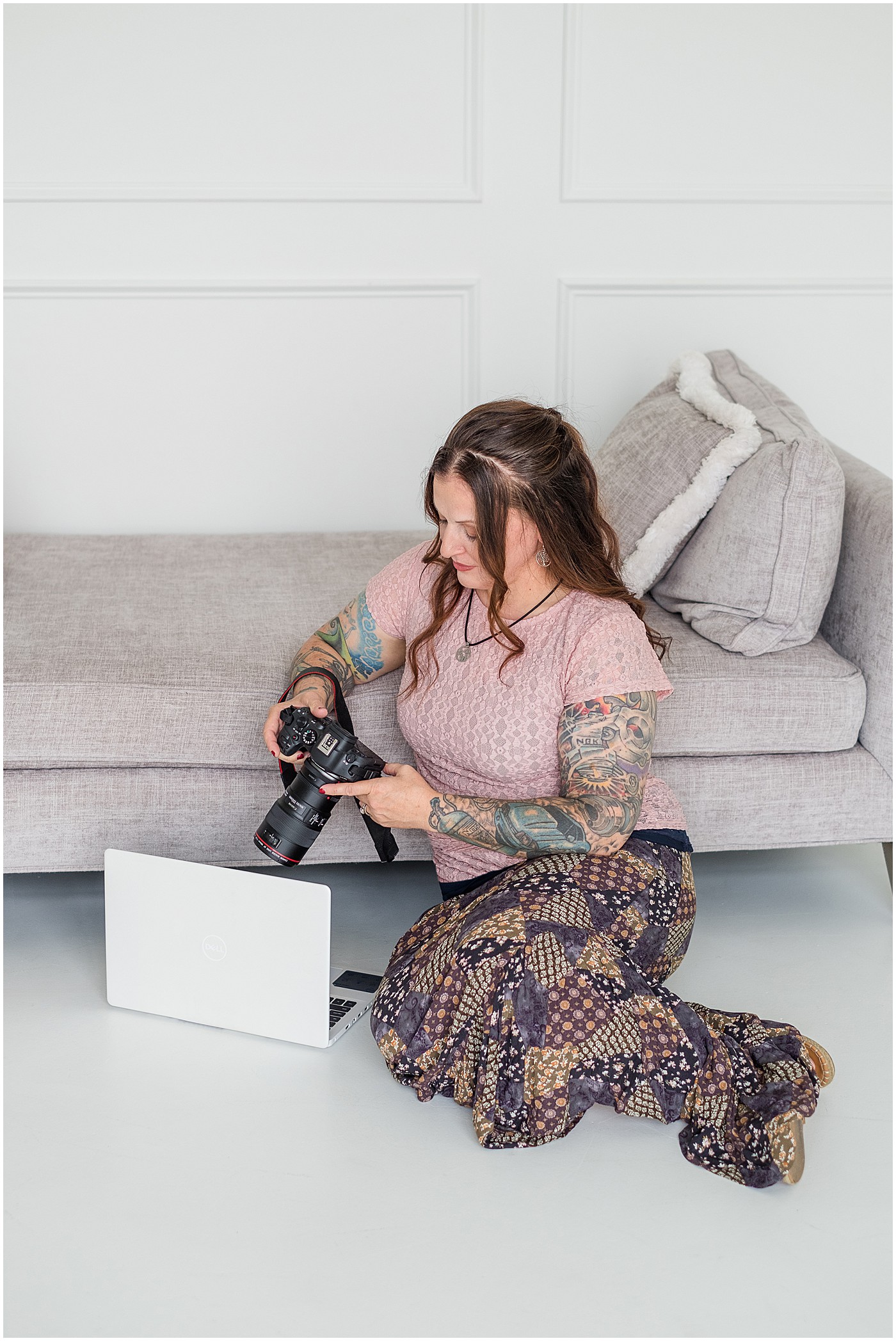 photographer sitting on floor looking at back of camera on her photography branding session