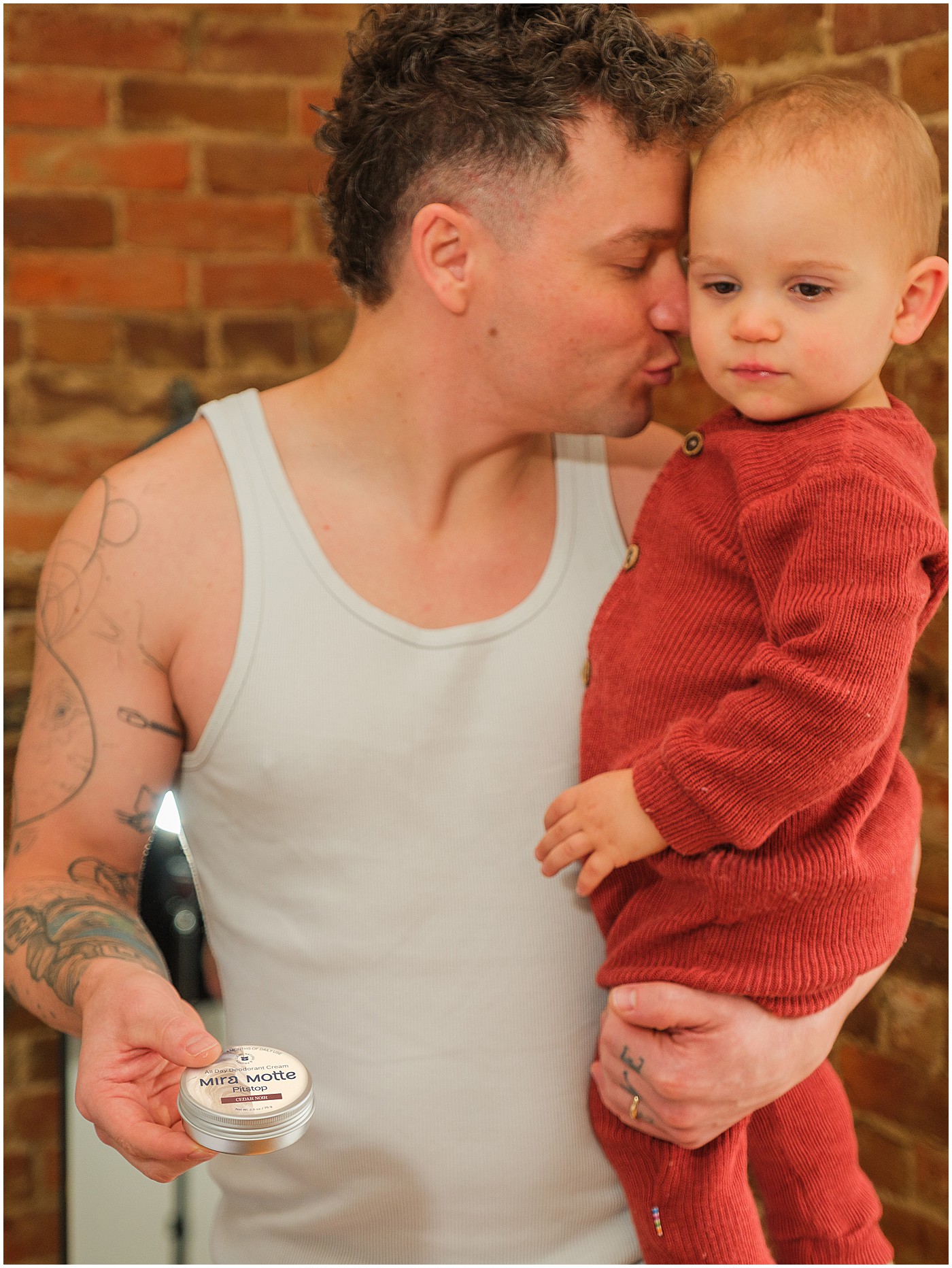 father holding his son in one arm and deodorant in the other hand